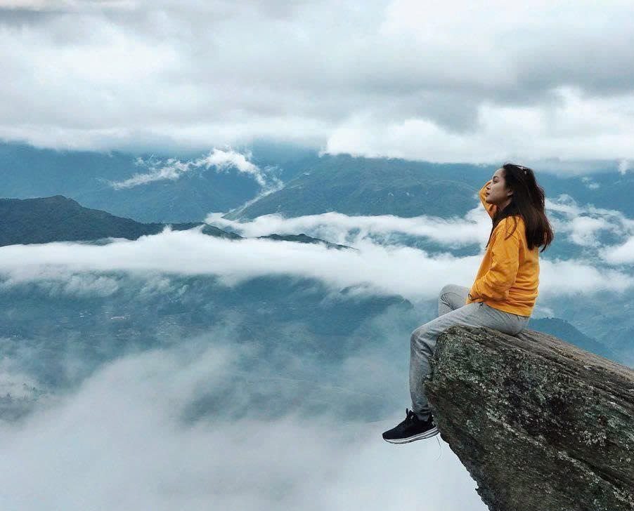 Hiker sitting above a valley filled with low clouds