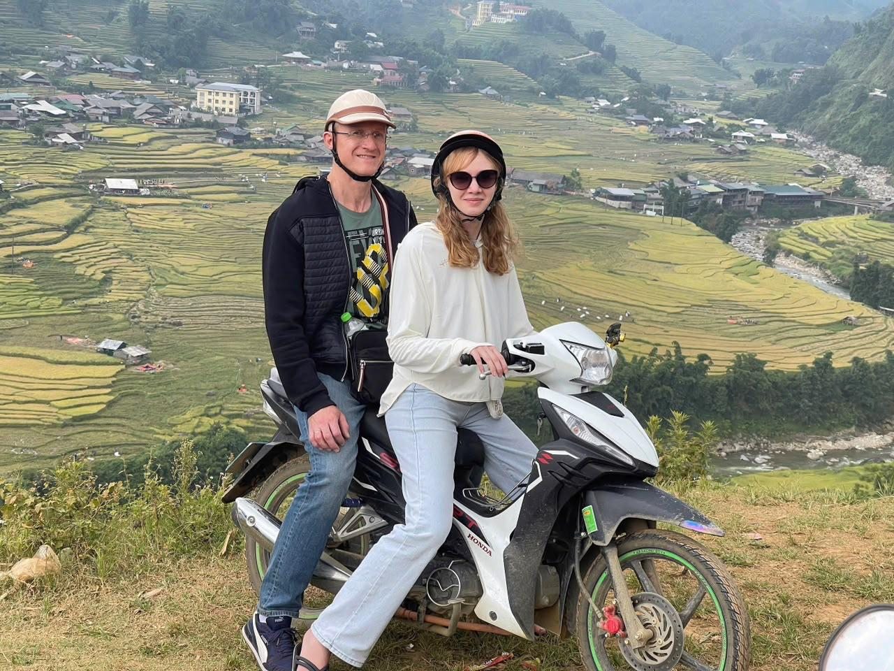 Guests and a local guide beside terraced rice fields and motorbikes